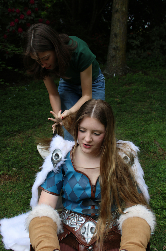 Pige sidder iført sit cosplay, en anden pige står bagved